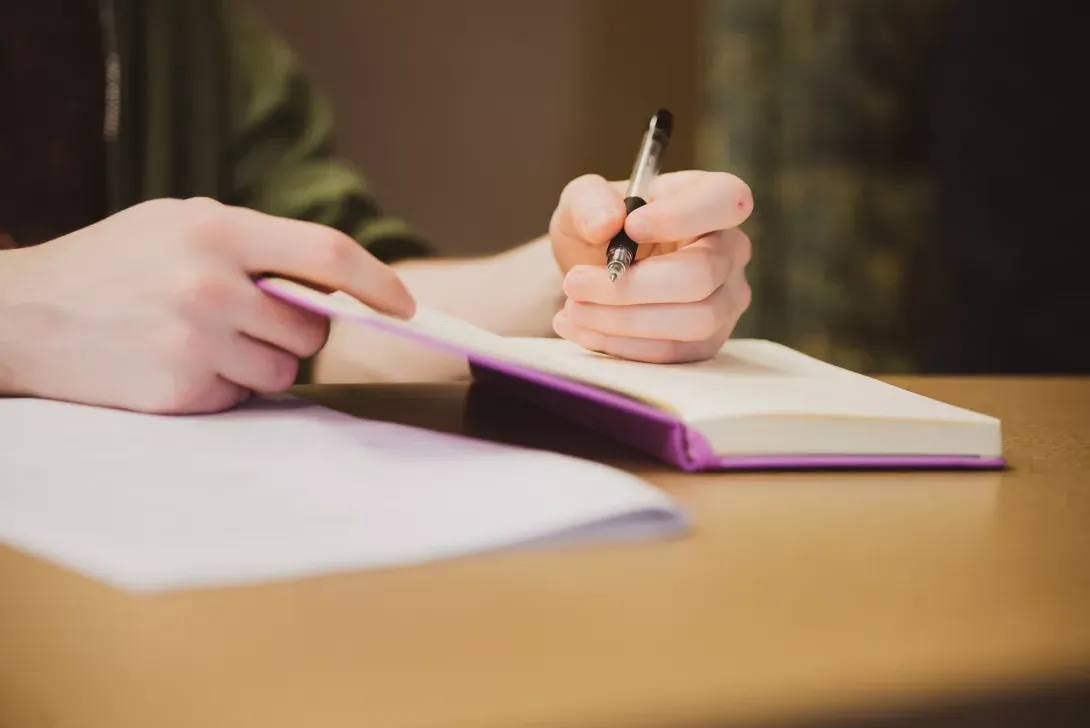 Close-up of student taking notes during MFA Summer Residency